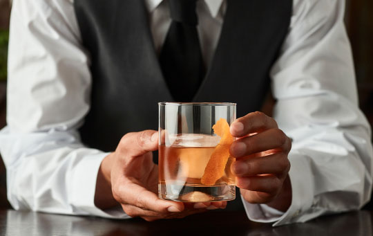 Image of waiter serving and Old Fashioned cocktail